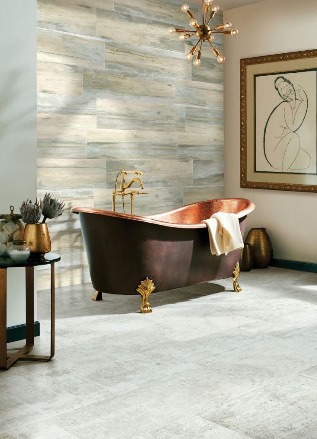 large grey tiles in a spacious bathroom with a freestanding copper tub and modern artwork